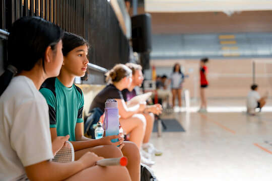 Junior badminton player wait on bench during tournament