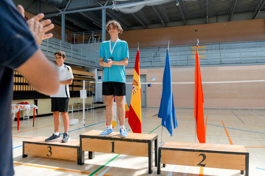 Junior badminton tournament winner on indoor award podium