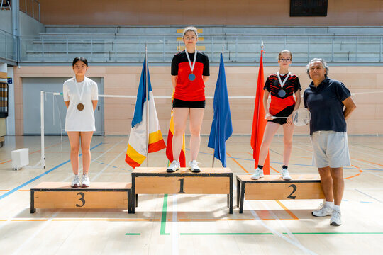 Young badminton players receive medals on indoor winners podium