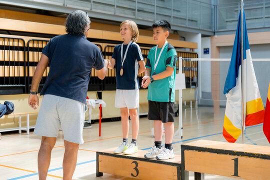 Junior badminton tournament medal ceremony in school gymnasium