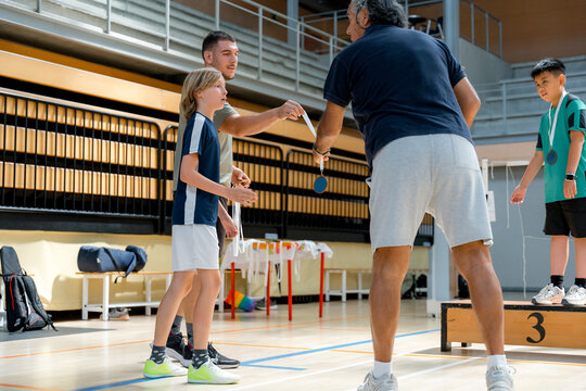 Official presents medal to young badminton player at ceremony