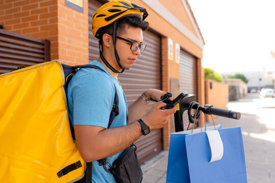 Delivery courier checking smartphone beside electric scooter