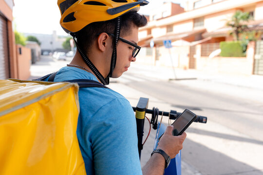 Scooter delivery rider check smartphone on urban street