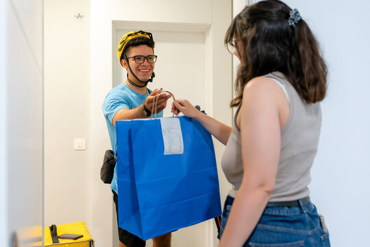 Scooter courier delivering shopping bag to customer at home
