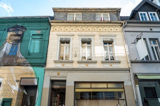 View of a historic building facade with ornate architectural details, large windows, and a storefront on the ground floor in Konigswinter, North Rhine-Westphalia, Germany.