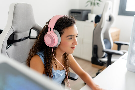 Young woman play computer game with pink headset