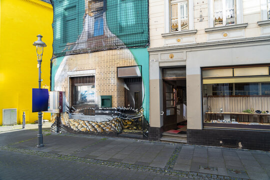 View of a building with a large mural and a shop window on a street in Konigswinter, North Rhine-Westphalia, Germany.