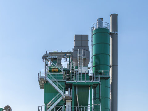 Aerial view of the Masfalt asphalt mixing plant featuring green industrial silos, metal staircases, and pipes against a clear blue sky in Dabrowa Gornicza, Slaskie, Poland.