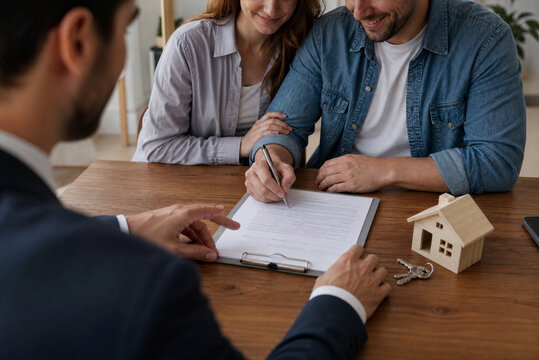 Couple Signing Mortgage Documents with Financial Advisor, Home Buying Process Home Buyers Reviewing Mortgage Agreement with Advisor, Real Estate Finance
Mortgage Signing Meeting with Couple