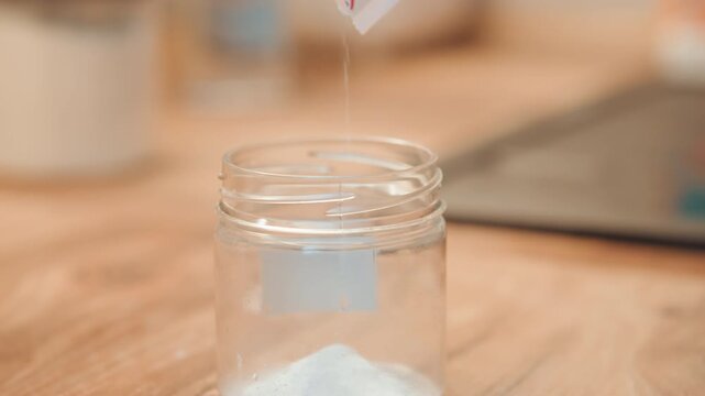 Precise preparation in kitchen. Closeup of powder in glass jar. Calm culinary setting with measured powder container. Detailed view of small powdered amount in glass jar on wooden surface
