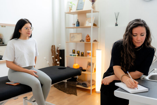 Osteopath writing treatment notes during patient consultation