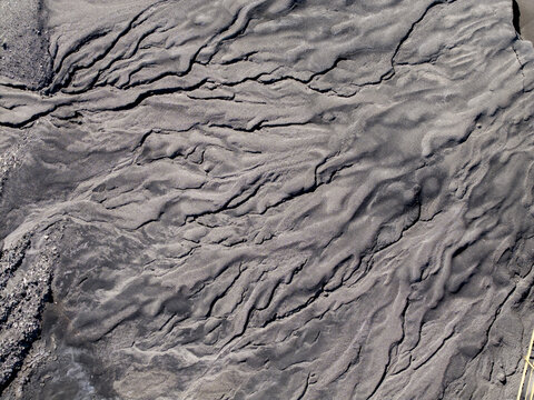 Aerial view of dark, eroded sediment patterns creating intricate textures and abstract shapes across the landscape in Poland.