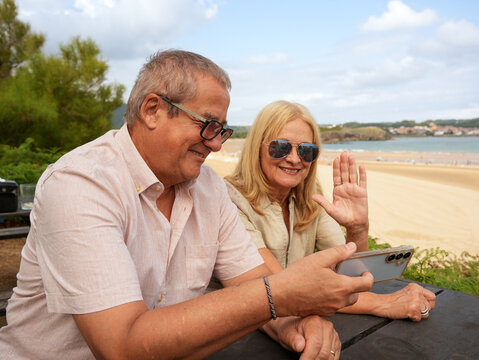 Senior couple video call at beach during vacation