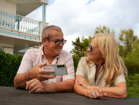Senior couple share smartphone moment near beach home