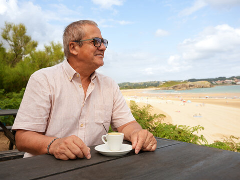 Senior man enjoy coffee with beach view on vacation