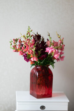 Pink flower bouquet in a red glass vase on table