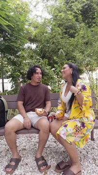 Young couple having fun eating exotic fruit in a park