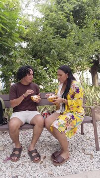 Young couple enjoying tropical street food on a park bench