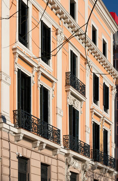 Neoclassical peach office building facade with wrought iron balcony