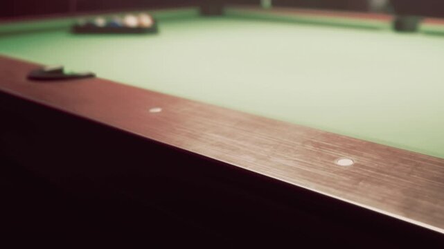 In a dimly lit room, people gather around a green pool table. They take turns aiming at colorful balls with cues in hand. Laughter and chatter fill the space.