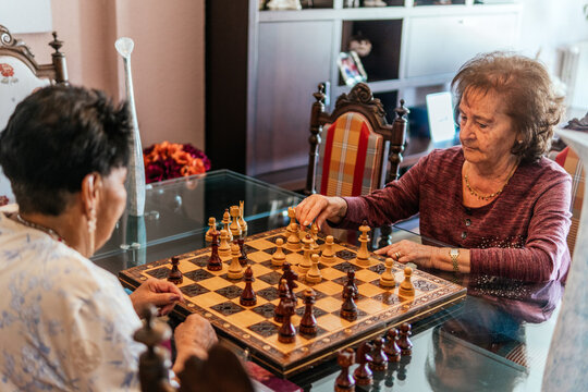 Senior women play chess together at home