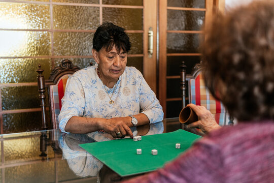 Senior women play dice game at home together