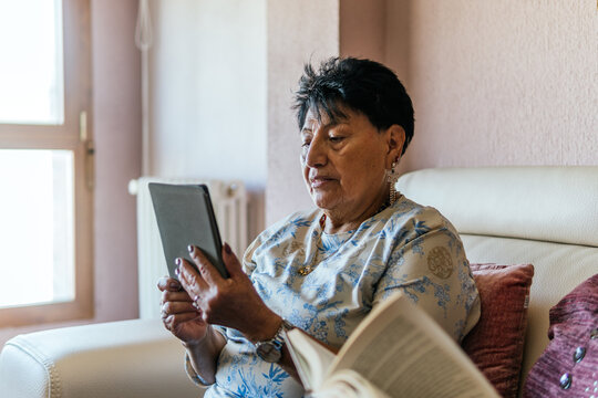 Senior woman read on e-reader at home beside friend
