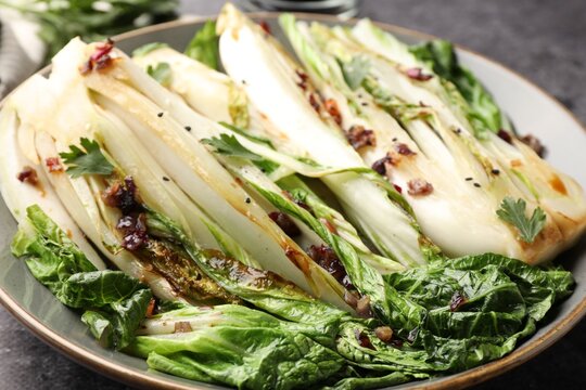 Tasty cooked bok choy cabbages with sesame seeds and sauce served on grey table, closeup