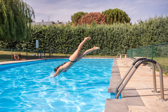 Woman dive into outdoor swimming pool on sunny day