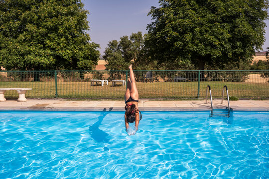 Woman dive headfirst into outdoor swimming pool