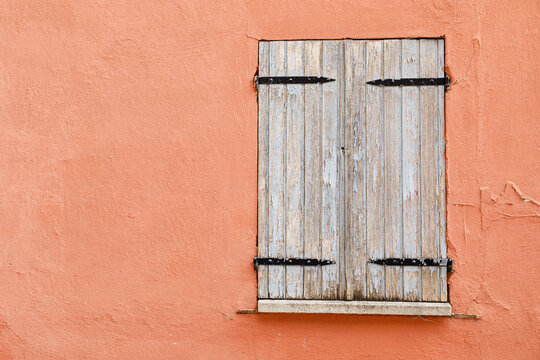 Vintage wooden window on a weathered plaster wall of an historic house