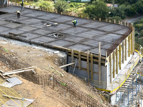 View of construction workers installing a rebar grid on a concrete slab at a hillside building site in Sariyer, Istanbul, Turkey.