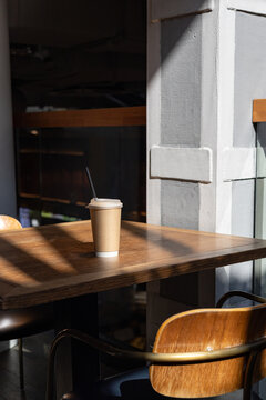 Takeaway coffee cup on sunlit table in modern food hall