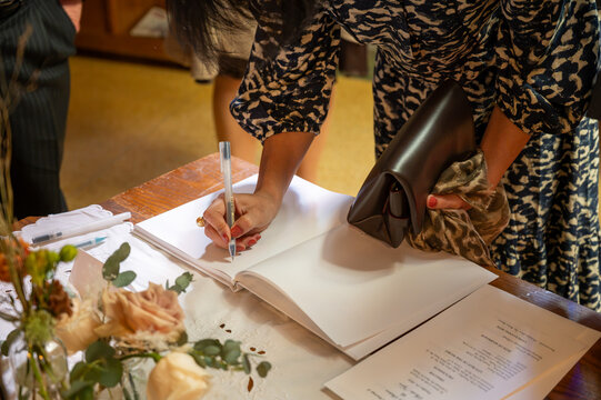 Close up of guest writing a personalized message in a wedding guest book