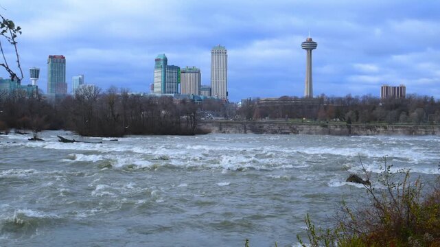 Upper Niagara River rapids are depicted in the photograph, with a panorama of Niagara Falls in Ontario, Canada