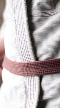 Vertical close up video of martial arts kimono go belt rank , close up selective focus, bokeh b roll martial arts, brown belt