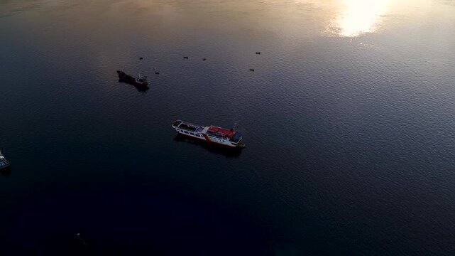 Aerial view of Ketapang Ferry Port with a ferry boat sailing on the calm sea during sunrise in Banyuwangi, East Java, Indonesia.