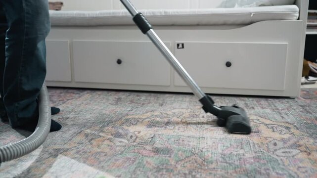 Wide sweep vacuum across patterned carpet. Calm domestic scene of slow vacuum strokes and steady rhythm, therapeutic chore mood with soft light, tidy living area, visible hose and blue canister
