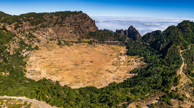 Aerial view of the Cova Crater volcanic landscape featuring agricultural fields surrounded by lush greenery and mountain ridges in Faja de Cima, Porto Novo, Cabo Verde.