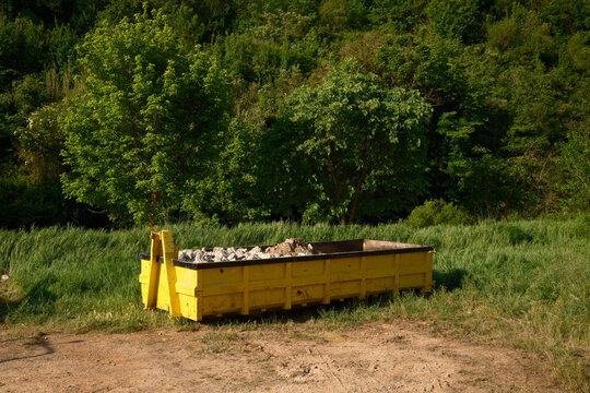 Yellow rubble container in rural Mura village landscape