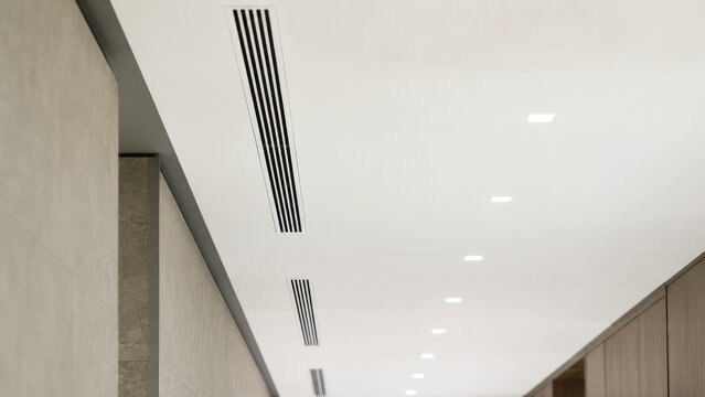Modern interior ceiling with linear air vents and recessed square downlights above a minimalist corridor