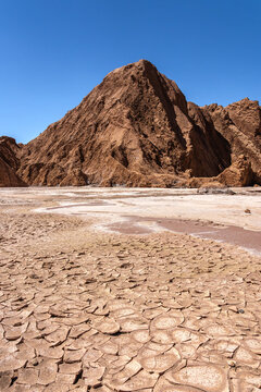 Arid mountain and cracked salt flat in Valle de Marte, Chile