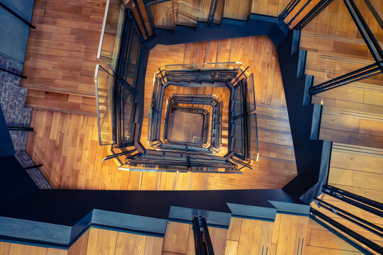 View of the modern spiral staircase with wooden steps and glass railings inside Tokyo Station in Chiyoda City, Tokyo, Japan.