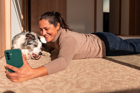 Woman take smartphone selfie with border collie at home