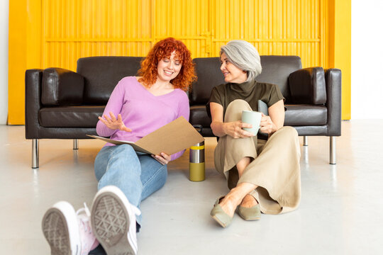 Two women reviewing folder during informal coffee break