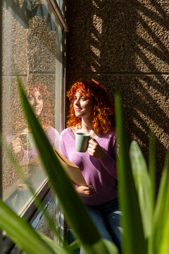 Woman with coffee and documents by sunlit window