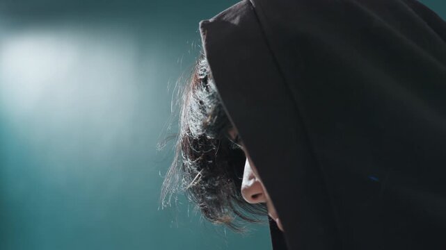Youthful hoodie portrait. Profile view of teen in hoodie capturing reflective light. Cinematicstyle side profile of young person donning hoodie with styled hair in artistic studio ambiance