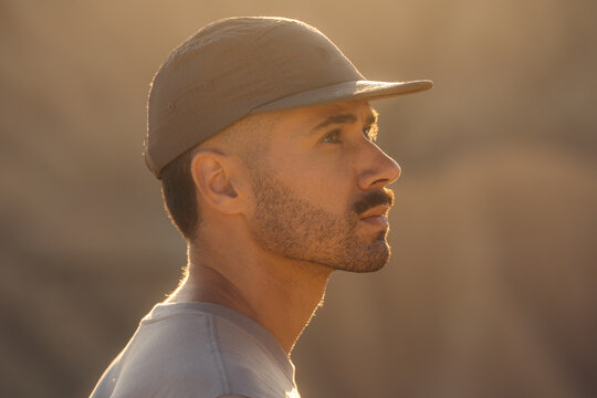 Bearded man in cap looking upward in golden sunlight