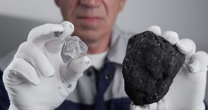 Worker holding rough diamond and coal at tabletop studio.