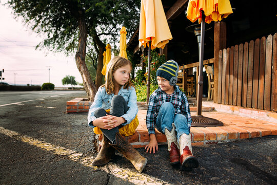 Brother and Sister Sitting Together in Park During Fall